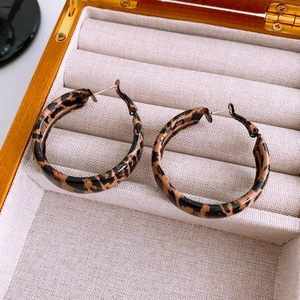 Close-up of vintage leopard print hoop earrings displayed in a wooden jewelry box
