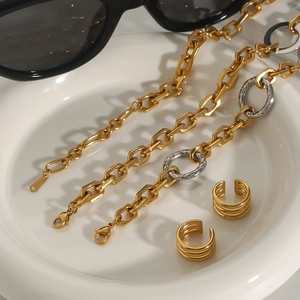 Gold stainless steel jewelry set with chain and layered ear clips on ceramic plate