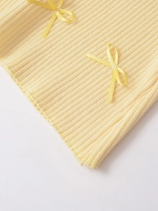 Gros plan sur le tissu en maille côtelée jaune clair avec des nœuds décoratifs en satin