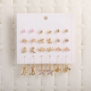 Set of 18 golden and pink bow heart star earrings displayed on a white card background