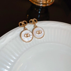 Detailed macro of gold flower heart earrings with white inlay and interlocking CD motif