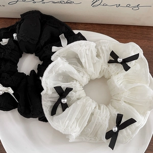 Detailed close-up of lace scrunchies with ribbon bows and pearls on a white tray