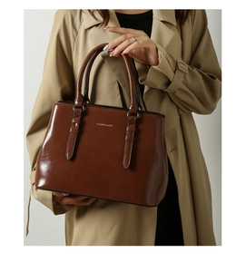 Detail of caramel glossy leather tote bag with metallic logo and sturdy double handles
