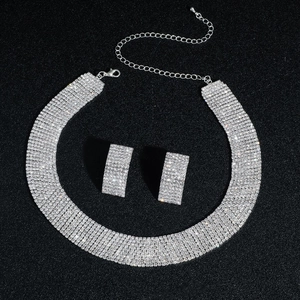 Detailed view of silver multi-layer rhinestone necklace and square stud earrings on black background