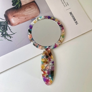 Close-up of portable acetate handheld mirror with floral pattern and round glass
