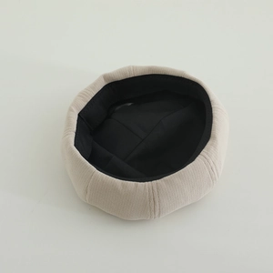 Close-up of beige knitted beret showing vertical texture and black inner lining detail