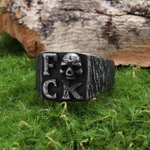Detailed macro shot of vintage gothic skull ring with FCK letter engraving on wood