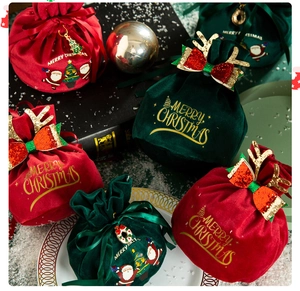 Close-up of red and green velvet Christmas gift bags with reindeer antlers and embroidery