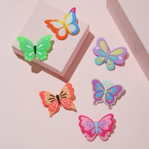 Flat lay of colorful PVC butterfly charms for party favors on a pink background