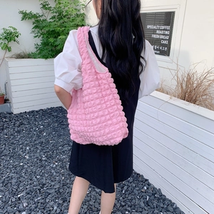 Detail view of pink bubble textured tote bag worn by model in minimalist outdoor setting