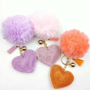 Three colorful plush pompom heart keychains with rhinestones and tassels in gold tone