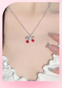 Dettaglio della collana con ciliegia e fiocco sulla clavicola con effetto scintillante