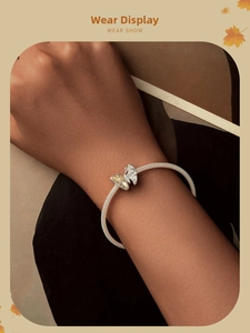 Close-up of a silver mesh bracelet with a butterfly charm featuring yellow and clear stones