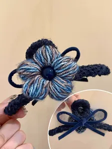 Détail d'une pince à cheveux fleurie tissée bleue avec perle centrale et dentelle