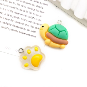 Macro shot of cute turtle and cat paw yellow resin charms for DIY jewelry making
