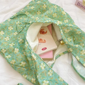 Close-up of green floral canvas tote bag showing large capacity for books and hand cream