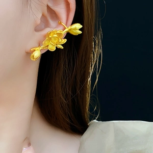 Detailed view of a gold-plated lotus flower ear cuff on model with a black background