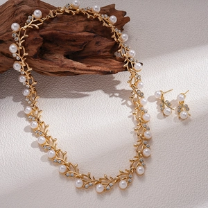 Elegant vintage gold branch jewelry set with pearls and rhinestones on wood background