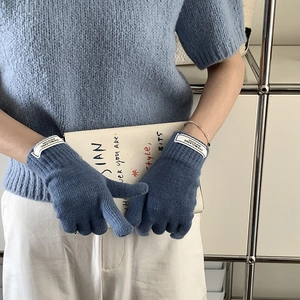 Detail of blue knitted gloves with denim classic labels shown in a lifestyle setting