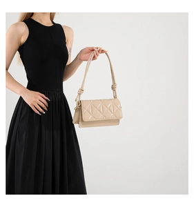 Detail of beige quilted crossbody bag with glossy leather finish and knotted strap