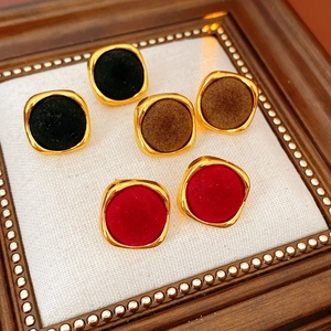 Détail de boucles d'oreilles carrées floquées en noir marron et rouge avec bord doré
