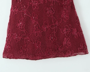 Detailed close-up of wine red lace fabric with 3D floral embroidery and sparkling sequins