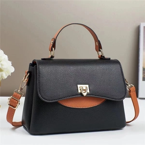 Chic black pebble leather handbag with brown handles and elegant gold metal clasp closure