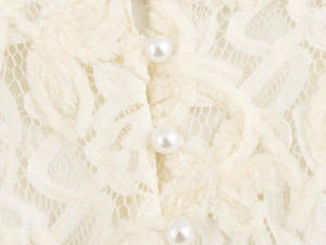 Gros plan détaillé d'une robe en dentelle blanche avec trois boutons de perles élégants