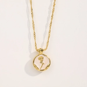 Detail of vintage gold rose pendant with white enamel inlay and embossed flower motif