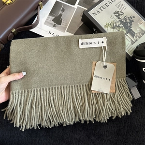 Detail of soft olive cashmere shawl featuring fine fringe tassels and elegant product tags