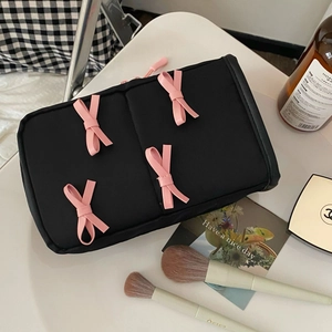 Top view of a black makeup bag with pink bows, featuring a smooth zipper closure
