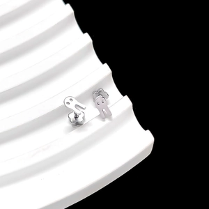 Detailed view of silver ghost-shaped stud earring on a white wavy stand over black background