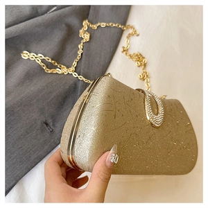 Detail of gold glitter evening clutch with rhinestone clasp and chain strap held by hand