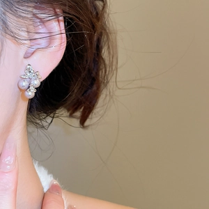 Close-up of elegant floral butterfly pearl earrings with crystals on woman's ear