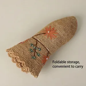 Handwoven raffia sun hat with floral embroidery and pearls, shown in foldable design