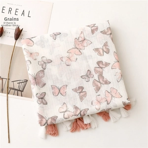 Close-up of pink butterfly prints and woven tassel details on linen texture shawl