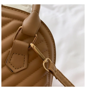 Close-up of quilted tan leather detail with golden hardware on shell crossbody bag