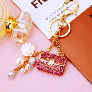 Detail of pink rhinestone handbag keychain with pearls and white rose charm