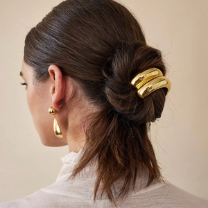 Detail of high-gloss 18K gold metallic hair ring and drop earrings on brunette hair