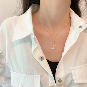 Detail view of double mermaid tail necklace with shell texture and sparkling zircon