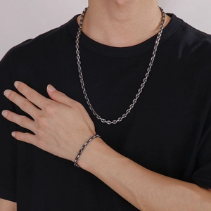 Detail shot of silver pig nose chain necklace and bracelet set on a person wearing black