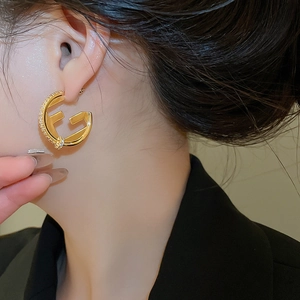 Close-up of 18K gold plated hollow circular earrings with cubic zirconia on model
