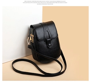 Detail of black pebbled leather crossbody phone bag featuring dual zippers and gold hardware