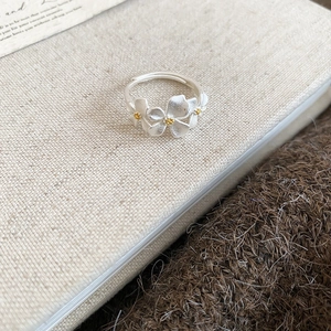 Close-up of adjustable silver flower ring with gold pistils on a textile background