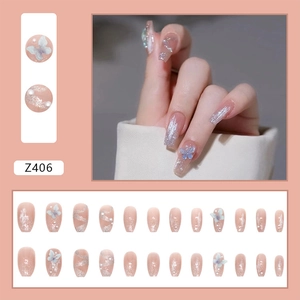 Detailed close-up of pink gradient press-on nails with blue 3D butterflies and pearls