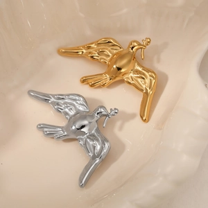 Elegant gold and silver peace dove brooches displayed on a beige textured jewelry tray
