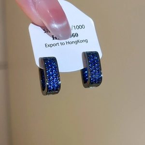 Close-up of blue zircon paved hoop earrings held on a silver material card