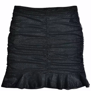 Close-up of a black ruched mini skirt with ruffled hem and subtle shimmering mesh texture