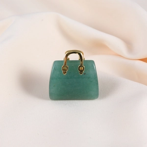 Detailed view of green jade mini handbag pendant with golden metal accents on soft fabric