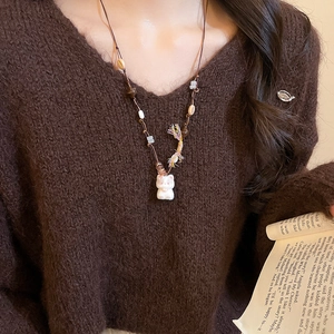 Close-up of retro cat pendant necklace with acrylic stars and tassel on a brown sweater
